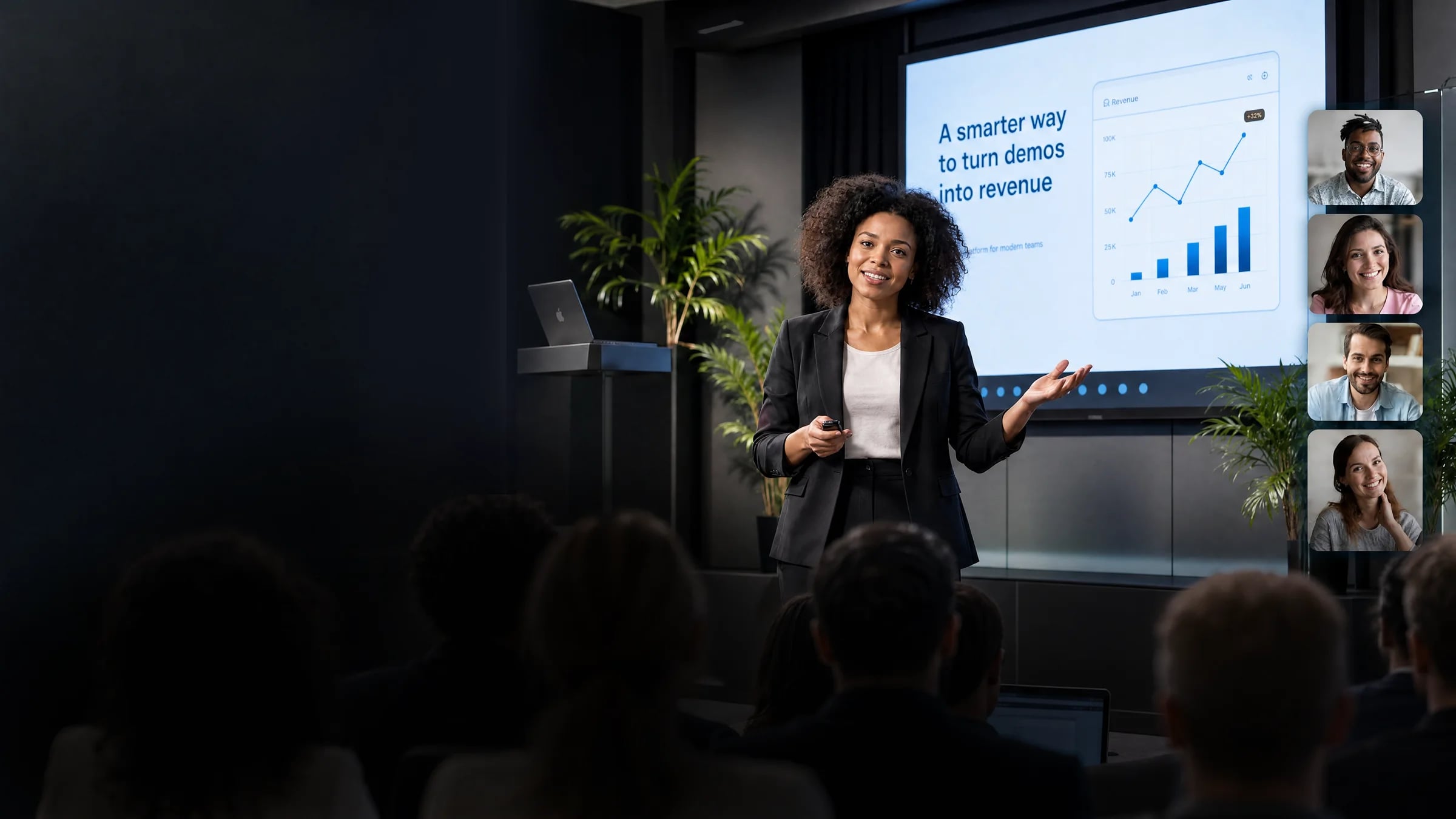 A sales rep running a live product demo in front of an in-person audience, with remote attendees joining by video and a revenue chart on screen